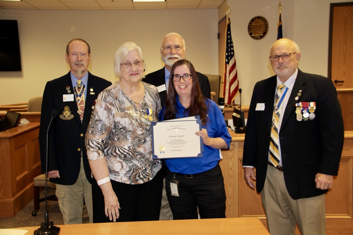 Local Paramedic Deborah Stancil, center, receiving the memorial Murray S. King Award from Kendra King and several Sons of the American Revolution in December. Photo by Shawn Jarrard