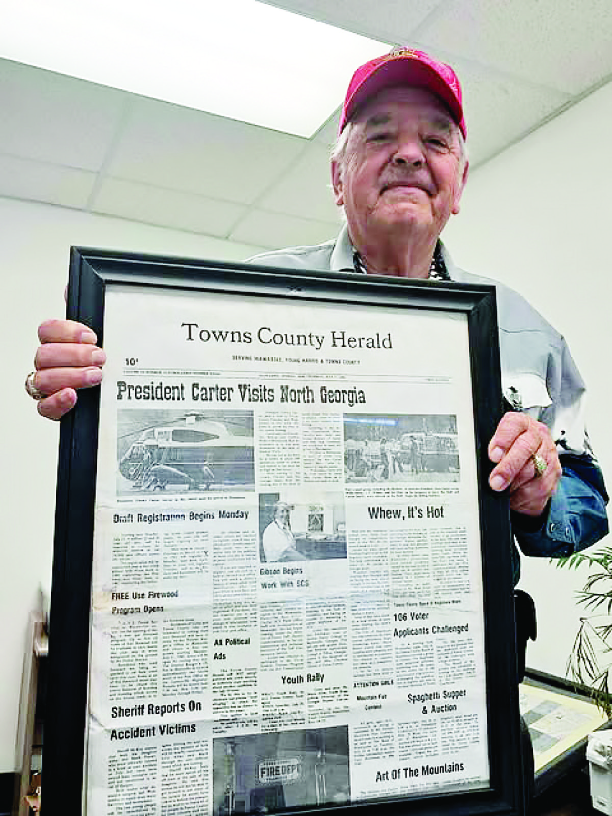 Richard Haigler holding a framed copy of the Towns County Herald’s coverage of President Jimmy Carter’s 1980 visit to Hiawassee. The president and friends went trout fishing here and his Secret Service stayed in the Deer Lodge cabins owned by Richard and his wife Willene. Photo by Becky Long/Clay County Progress