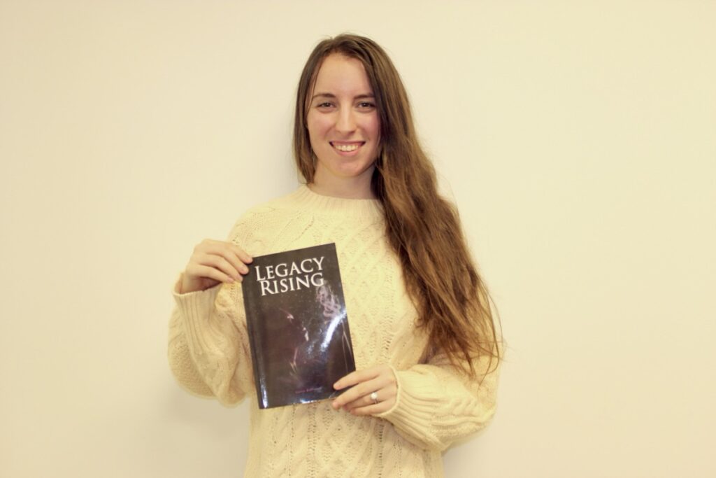 Casey Robinson is an up-and-coming local novelist, pictured here holding her first published work, “Legacy Rising.” Photo by Brittany Holbrooks