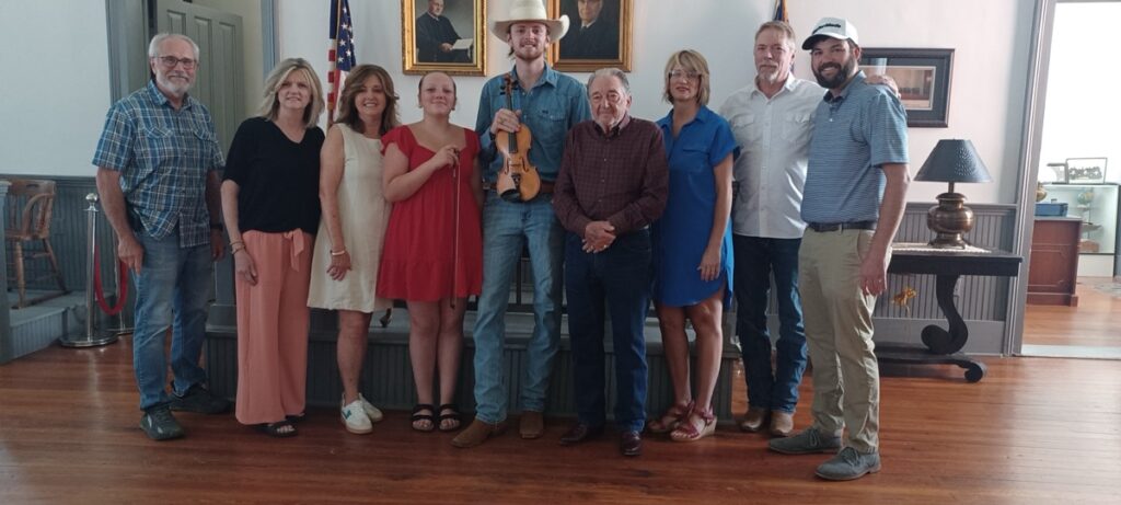 (L-R) Historical Society Member Mickey Cummings with the late Randall Collins’ daughter Jamie Shook, daughter Sherri Jones, granddaughter Finley Collins, grandson Easton Collins, brother F.C. Collins, daughter-in-law Shawna Collins and son Benny Collins, plus Historical Society President Mike Cook. Photo by Brittany Holbrooks