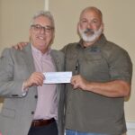Rotary Club of Union County President Chuck Henz presenting a donation to retired Air Force Command Chief Master Sgt. William Markham for his nonprofit specializing in helping veterans secure the benefits they deserve. Photo by Brittany Holbrooks