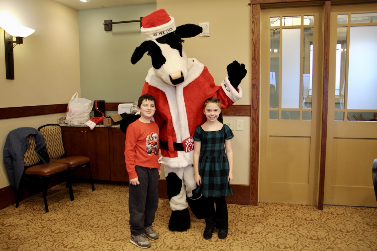 Axel Mashburn and Aundreah Rubio, both 8, posing with the Chick-fil-A Cow, who assisted the Breakfast with Santa event sponsored by the chamber and United Community Bank Dec. 6. Photo by Shawn Jarrard