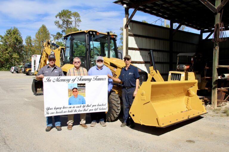 (L-R) Road Supervisor Christian Edwards, County Manager Tony Hughes, Commissioner Harold Collins and Maintenance Shop Supervisor Charles “Snuffy” Wright met last week to dedicate the new backhoe to Tommy Tanner. Photo by Shawn Jarrard