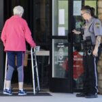 A Union County deputy sheriff holding the door for a local voter during the second Saturday of early voting. Photo by Shawn Jarrard