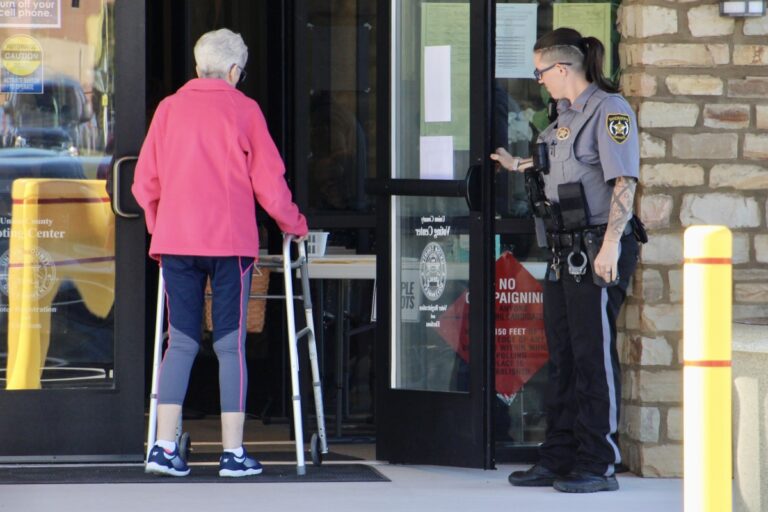 A Union County deputy sheriff holding the door for a local voter during the second Saturday of early voting. Photo by Shawn Jarrard